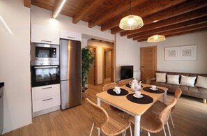 Eine moderne Küche mit Einbauofen, Kühlschrank und einer Essecke mit Tisch für zwei Personen.