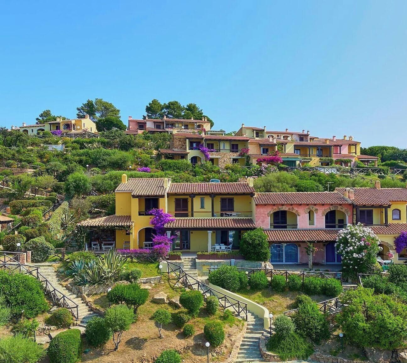 Una zona residencial en una ladera con casas escalonadas, una escalera que sube y abundante vegetación.
