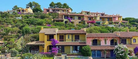 Una zona residencial en una ladera con casas escalonadas, una escalera que sube y abundante vegetación.