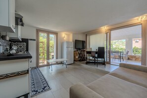 Una sala moderna con un sofá, una mesa de comedor con sillas, una zona de cocina con estufa y un televisor.