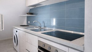 Una cocina moderna con lavadora integrada, un lavamanos doble y una estufa.