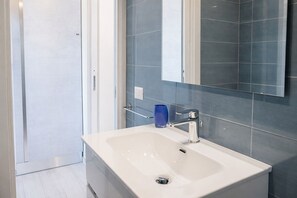 A bathroom with a white sink, a blue glass, and a mirror.