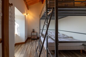 Habitación con literas, una mesita de noche pequeña y una lámpara fijada a la pared.