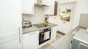 Ett modernt kök med vita skåp, en inbyggd ugn, en brödrost och ett fönster med utsikt.