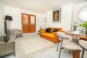 A living room with a sofa, chairs, a coffee table, a TV, and a lamp. - The Residence by Guestz (Cheltenham)