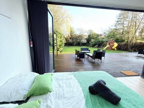 A bedroom with a large bed, green and white bedding, a green area rug, and a view of an outdoor deck with outdoor furniture. - 2 Bed - Sleeps 4 - Hot Tub & Bbq (London)