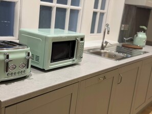A kitchen with a toaster, a microwave, a sink, and a window with blinds. - 2 Bed - Sleeps 4 - Hot Tub & Bbq (London)