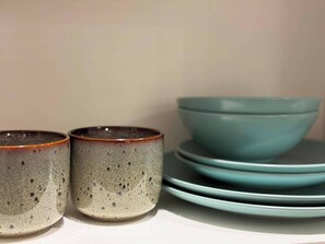 A stack of ceramic bowls and cups on a shelf. - 2 Bed - Sleeps 4 - Hot Tub & Bbq (London)