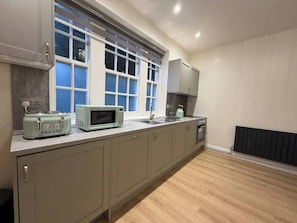 A kitchen with a window, a microwave, a toaster, a sink, and a stove.