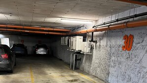 Un garaje de estacionamiento con pisos de concreto, espacios delimitados y una pared con el número 30.