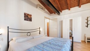 A bedroom with a bed, a wooden ceiling, a white wall, and a door. - Apartment 'Appartamento Borgo' with Mountain View, Wi-Fi and Air Conditioning (San Felice del Benaco)