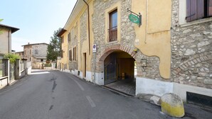 A narrow street with stone buildings, a no parking sign, and a yellow bollard. - Apartment 'San Felice' with Private Terrace, Wi-Fi and Air Conditioning (San Felice del Benaco)