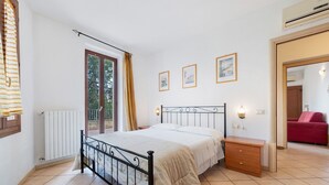 A bedroom with a bed, bedside table, and a window with curtains. - Apartment 'San Felice' with Private Terrace, Wi-Fi and Air Conditioning (San Felice del Benaco)