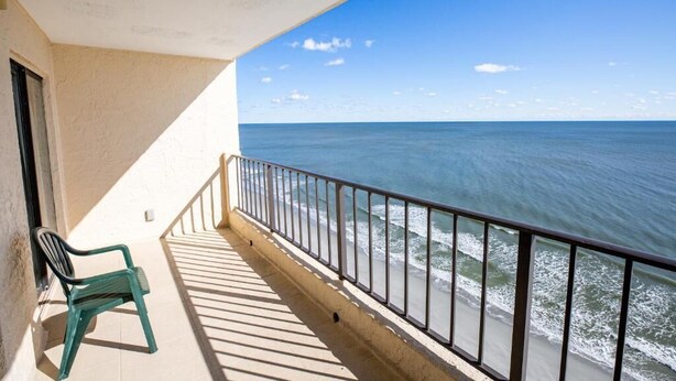 Varanda com vista para o oceano, uma cadeira e um corrimão.