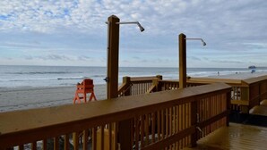 Una terraza de madera con barandilla que da a una playa.