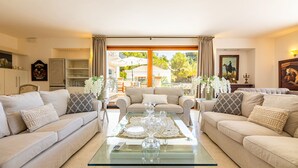 Un salon avec deux canapés, une table basse en verre et une vue sur l’extérieur.