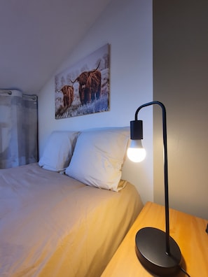 A bed with white bedding, a painting of yaks on the wall, and a bedside table with a lamp. - Immersion at Le Trappeur Atypique Vendée-At the foot of the Cathedral-With parking (Luçon)