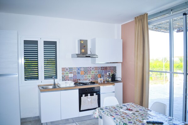 Una cocina pequeña con ventana, estufa y lavamanos.