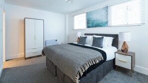 Een slaapkamer met een bed, nachtkastjes, een kledingkast en een groot abstract schilderij aan de muur.