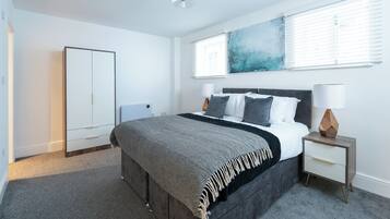 A bedroom with a bed, bedside tables, a wardrobe, and a large abstract painting on the wall.