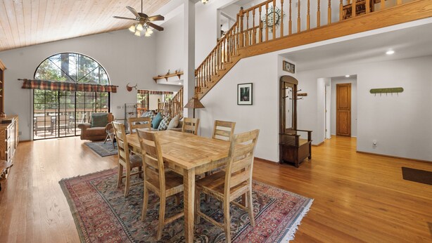 A spacious dining area with a wooden table and chairs, a large rug, and a staircase leading to an upper level. - Modern Mountain Chalet w/ Hot Tub, Near the Slopes, Lake & Village (Big Bear Lake)