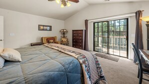 A bedroom with a bed, a ceiling fan, a dresser, a lamp, and a view through a sliding glass door. - Modern Mountain Chalet w/ Hot Tub, Near the Slopes, Lake & Village (Big Bear Lake)