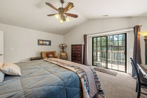 A bedroom with a bed, a ceiling fan, a dresser, a lamp, and a view through a sliding glass door. - Modern Mountain Chalet w/ Hot Tub, Near the Slopes, Lake & Village (Big Bear Lake)