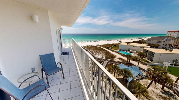 A balcony with two chairs, a pool, and a beach view. - Seacrest 601b 2 Bedroom Condo (Fort Walton Beach)