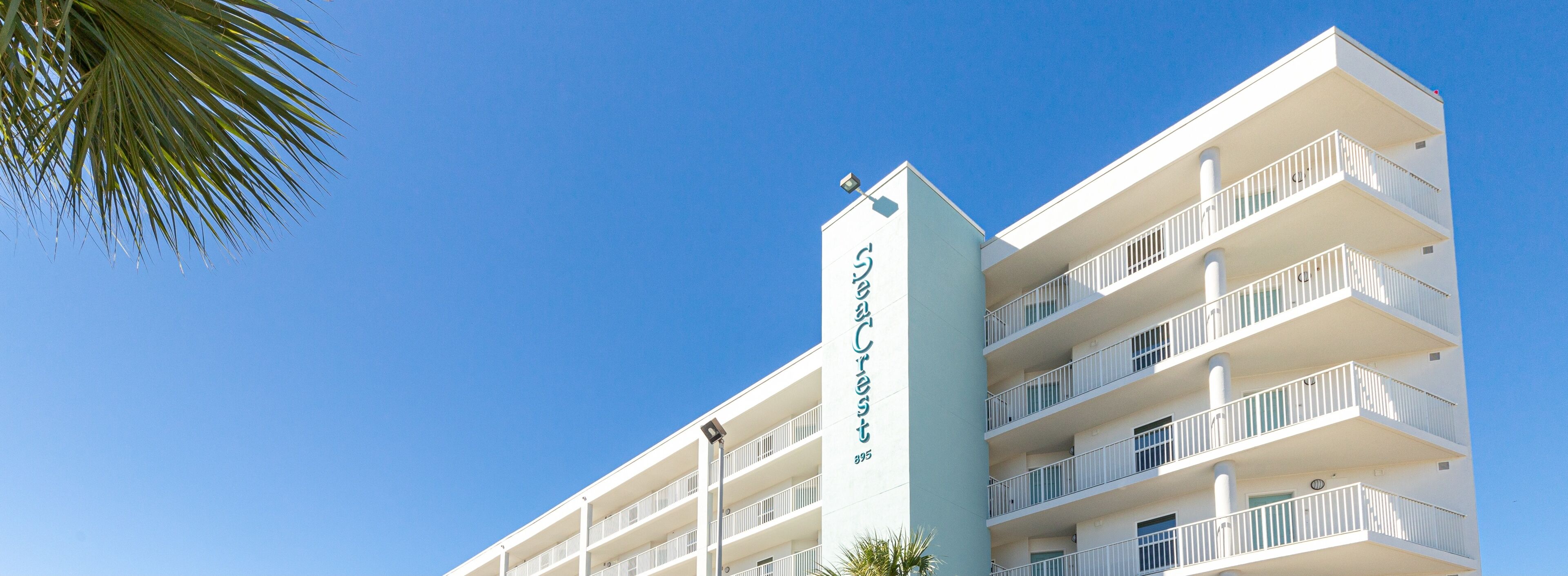 A multi-story hotel with balconies and a clear blue sky.