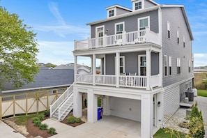 Ein zweistöckiges Haus mit Balkon, Garage und einer Treppe, die zum oberen Stock führt.