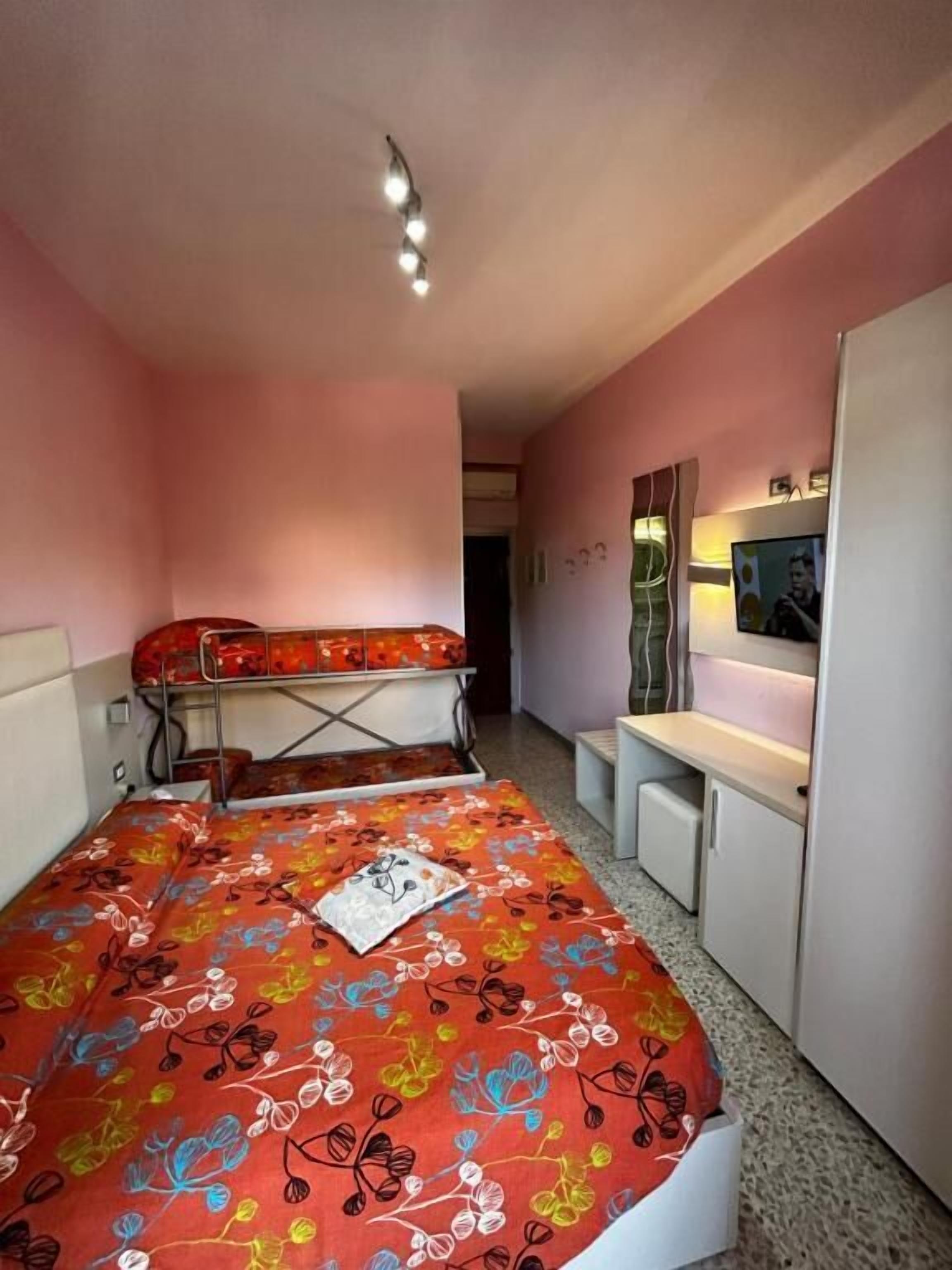 Un dormitorio con una cama litera, un escritorio, una silla y un televisor.