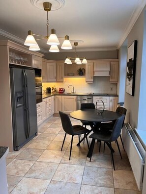 A modern kitchen with a central island, a refrigerator, and a dining table with chairs. - No 10 Bridge Street Westport (Westport)