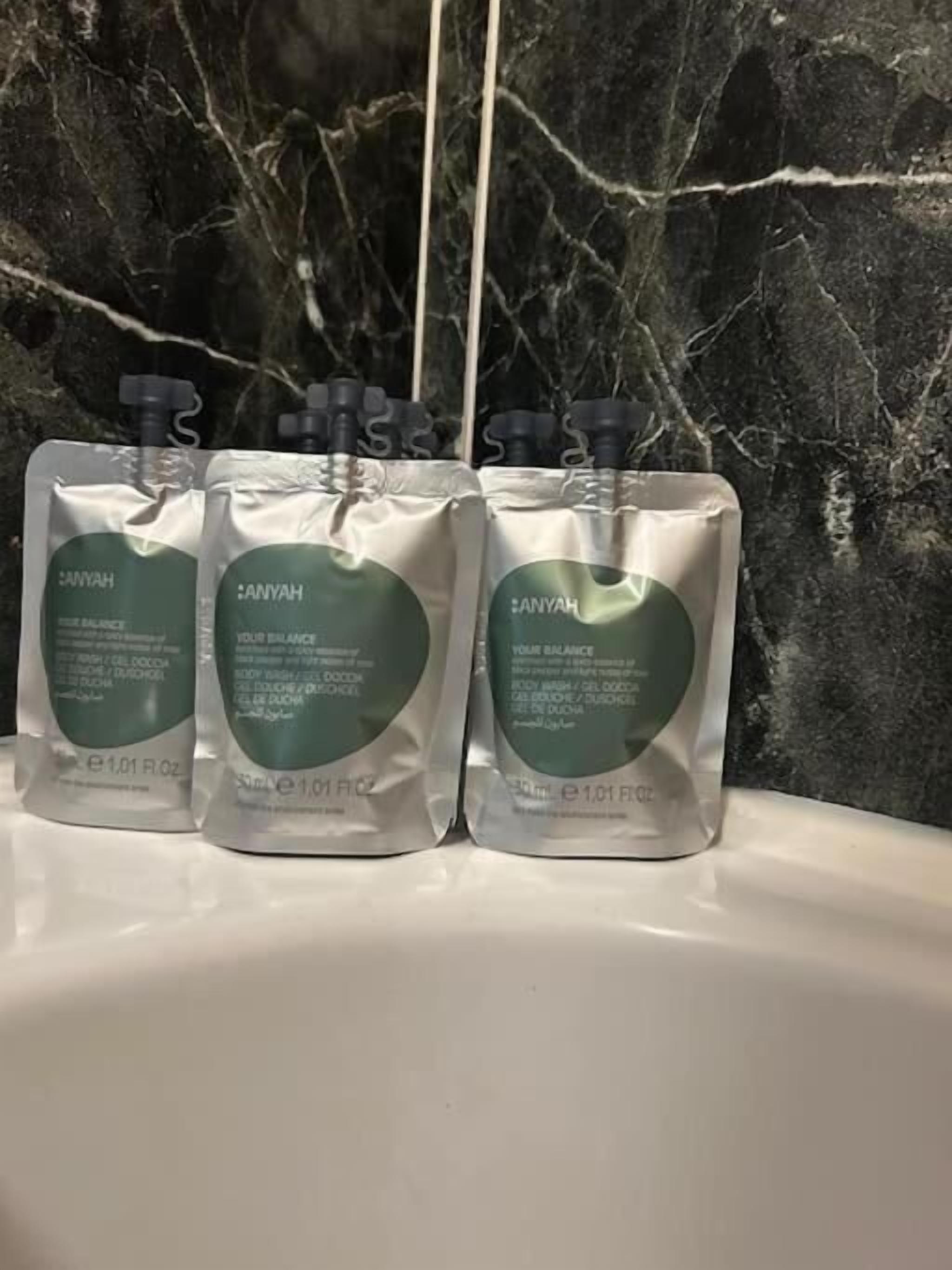 Three Anyah body wash bottles on a white surface with a marble background.