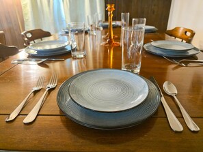 Une table à manger dressée avec des assiettes, des couverts, des verres et une bougie.