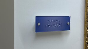 Una placa azul sobre una pared blanca con el texto 'STANZA FATTORI'.