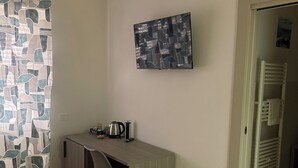 Una habitación con escritorio, silla, cama y zona de ducha.