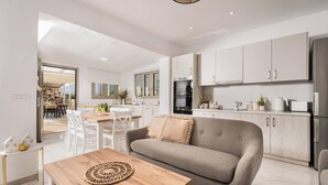 Eine moderne Küche mit weißen Schränken, einem grauen Sofa und einem Holztisch.