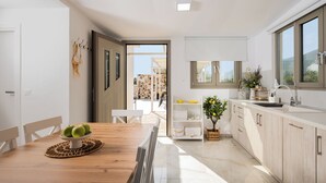 Eine moderne Küche mit Esstisch aus Holz, weißen Schränken und Blick ins Freie.