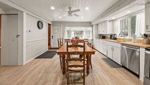 Una cocina moderna con una mesa de comedor de madera, armarios blancos y un lavavajillas integrado.
