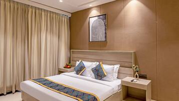Una habitación de hotel moderna con una cama grande, una mesita de noche, un abanico de techo y una obra de arte colgada en la pared.