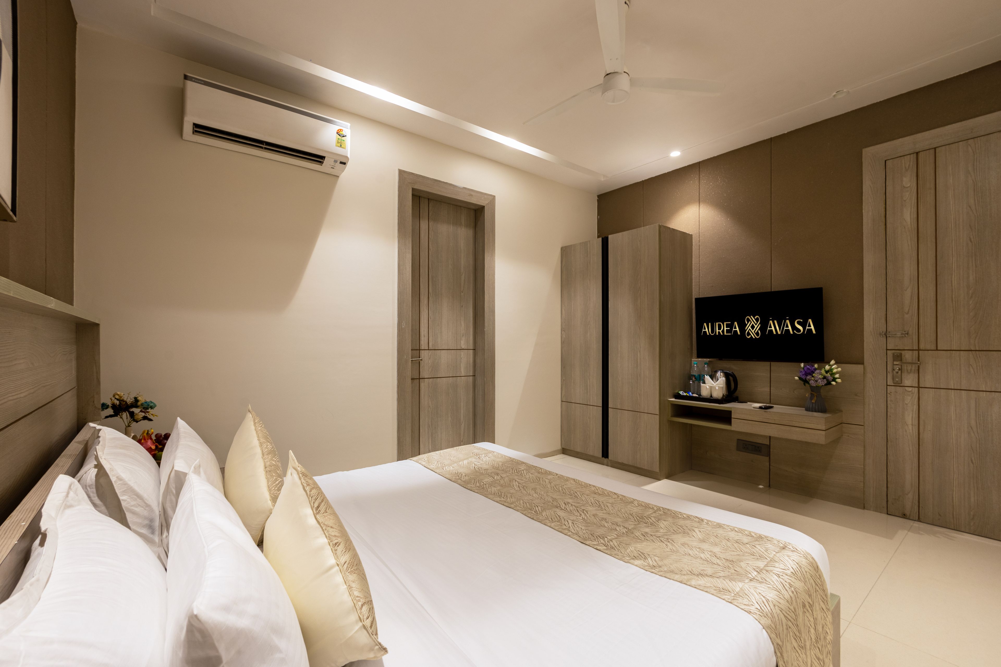 Een moderne slaapkamer met een bed, garderobe, kaptafel en een flatscreen-tv.
