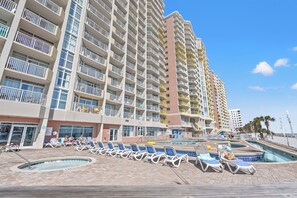 A hotel with multiple balconies, a pool area with sun loungers, and a clear blue sky. - Bay Watching the Waves, Large 2 BR with Fitness Center Access in NMB (North Myrtle Beach)