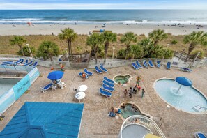 Ein Strandhotel mit Poolbereich, Liegestühlen und einem Rettungsturm.