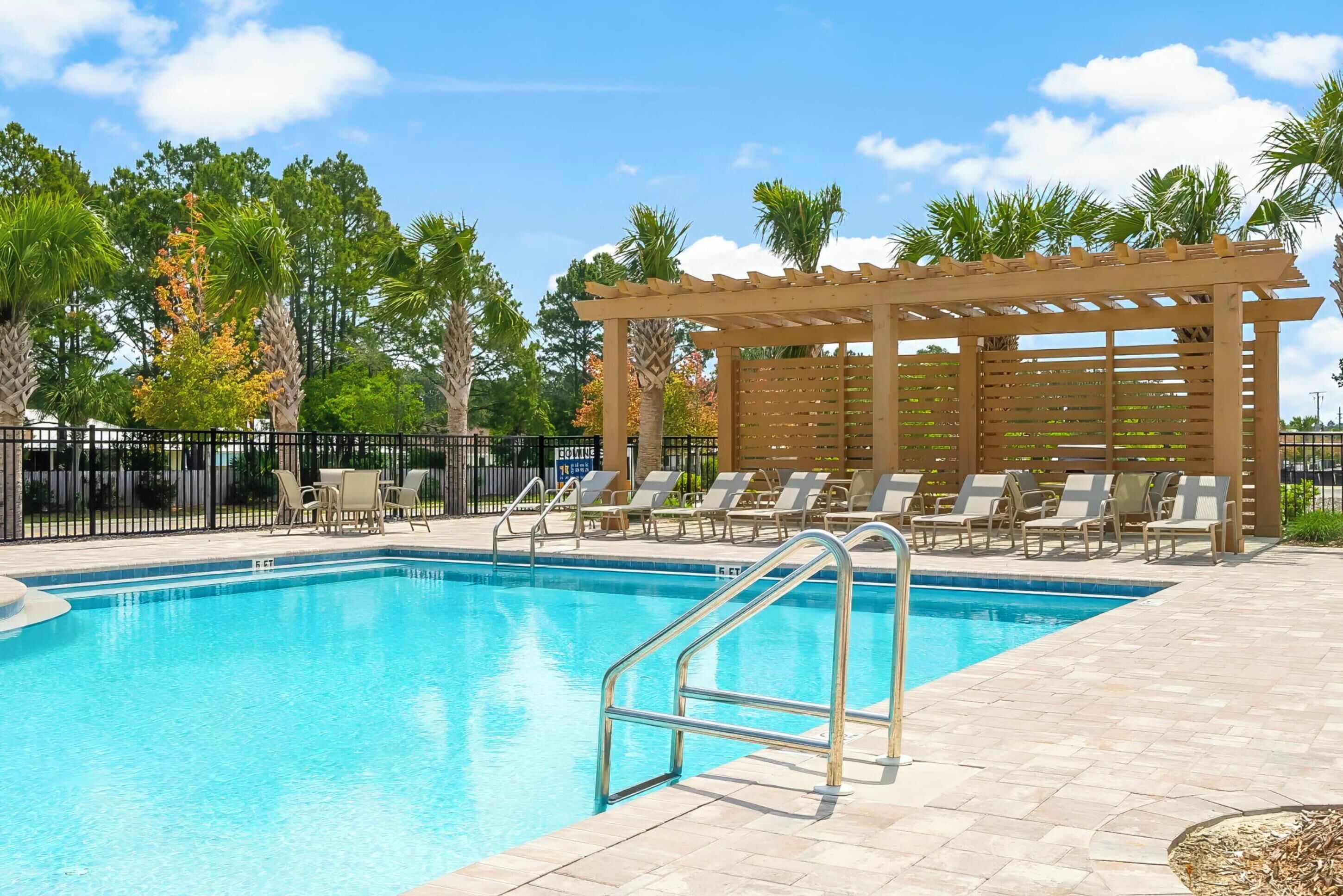 Une piscine avec des chaises longues et une pergola.