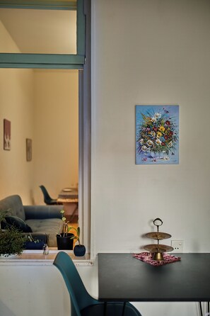 Une pièce comprenant une table à manger, des chaises, une plante en pot et un tableau accroché au mur.