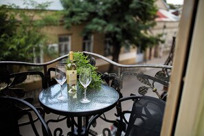 Une table ronde en verre, sur laquelle se trouvent une bouteille et deux verres, entourée de chaises en métal noir.