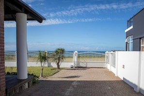 A paved patio with a white fence, a palm tree, and a view of the ocean. - The Al Marjan Schoenmakerskop (Gqeberha)