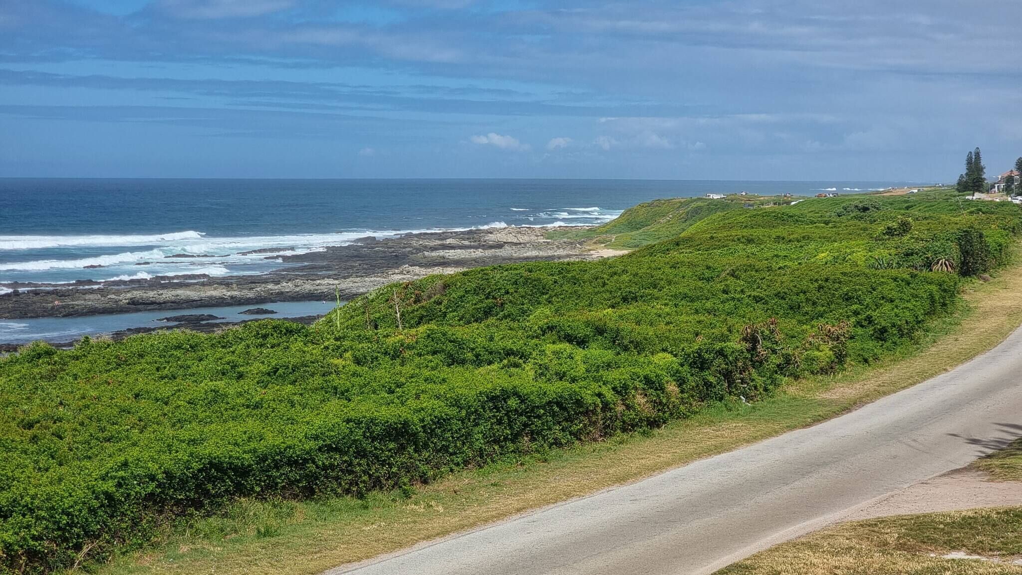 A coastal road with lush greenery and rocky coastline.