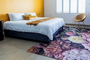 A bedroom with a bed, a chair, a window, and a floral rug.
