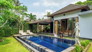 A swimming pool with lounge chairs, a statue, and a modern house with large windows. - Alpin Resort and Villa Ubud (Ubud)